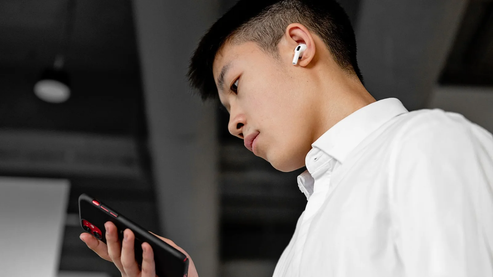 Auriculares inalámbricos junto a un teléfono y su estuche de carga