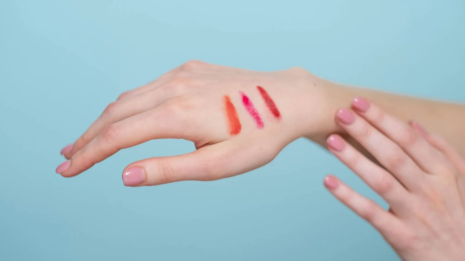 Barras de labios y muestras de color sobre una mano bajo luz natural